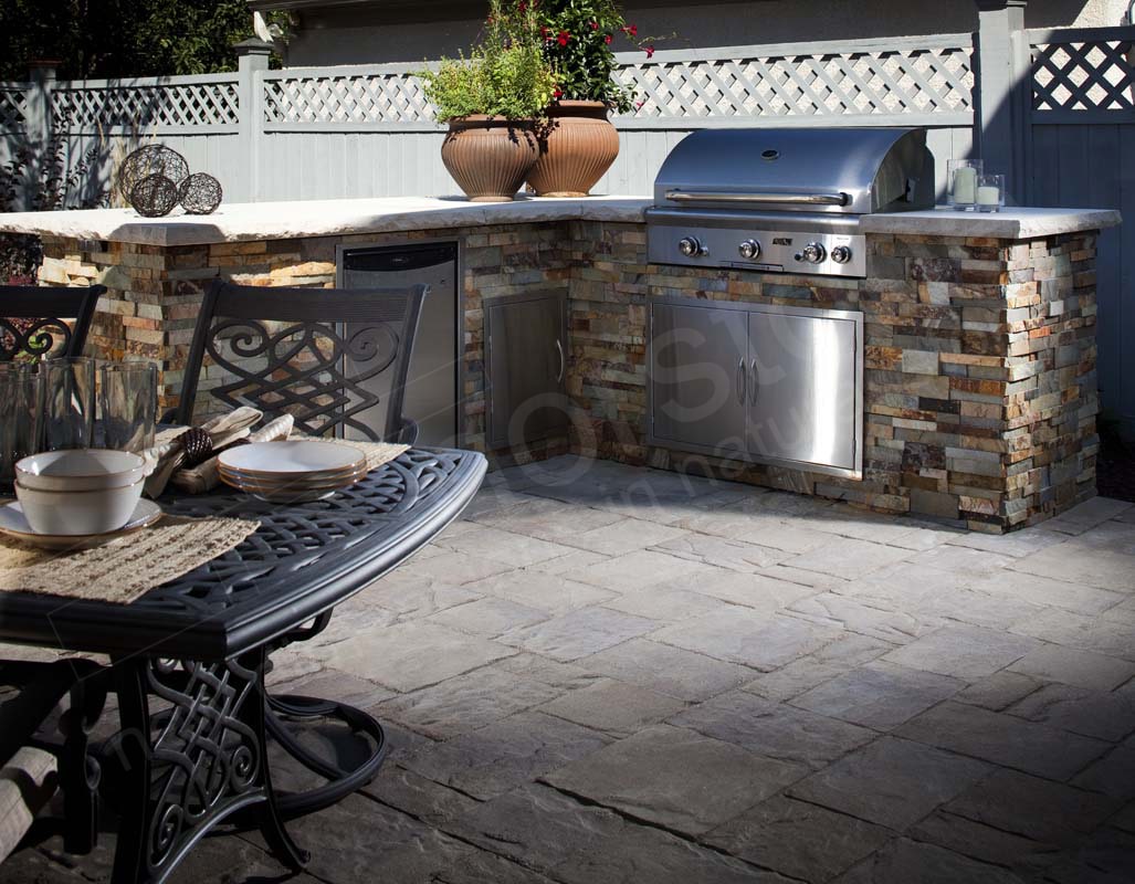 Prefab outdoor grill island and summer kitchen with a metal substrate that has been clad with a stone veneer